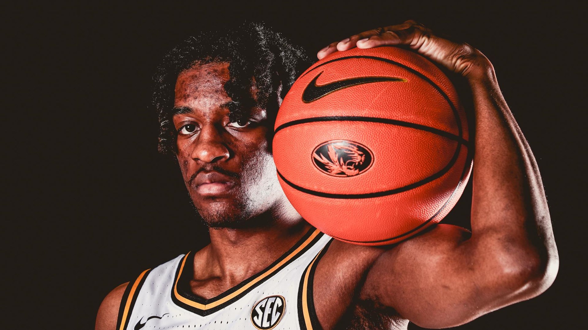 sean east holds mizzou basketball on his shoulder